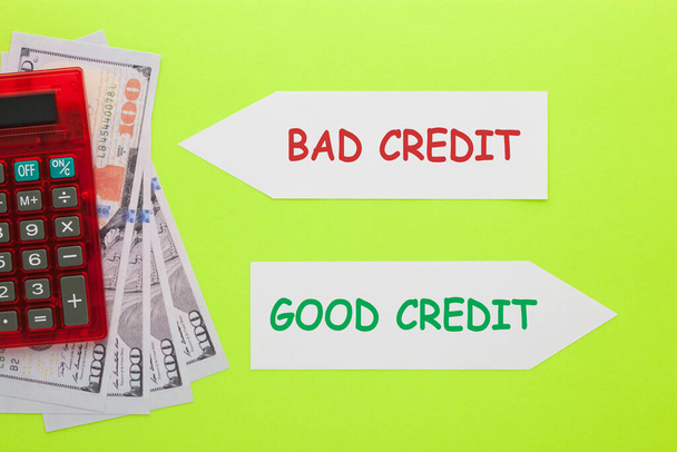 Good credit versus bad credit written on paper arrow with hundred dollar bills and calculator. Business concept. - Fotoğraf, Görsel