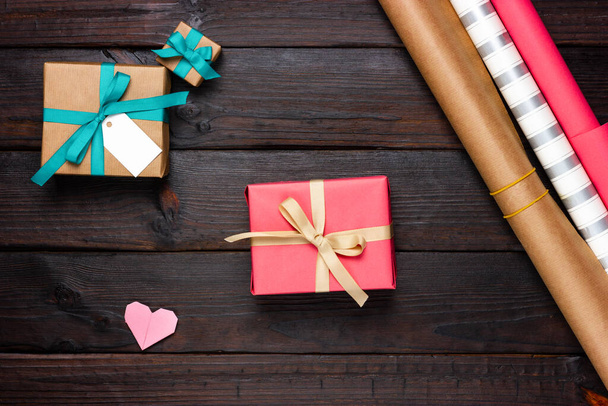 Several gift boxes, wrapping paper and paper hearts on a dark wooden table. Festive, romantic Flat Lay - Foto, Imagem