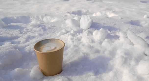 Paper cup with aromatic, hot latte coffee on fluffy, frosty snow. Aromatic composition with natural. - Photo, Image