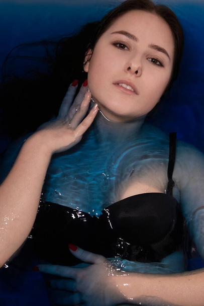 ritratto di attraente donna bruna in topless in liquido blu. in vasca con acqua colorata. ragazza che affoga. copia spazio - Foto, immagini