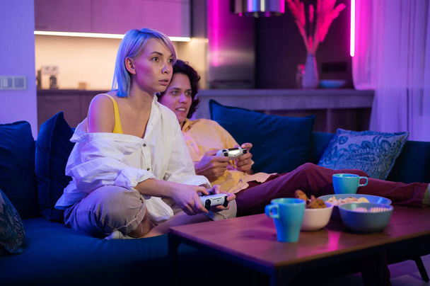 Jovens brancos alegres marido e mulher jogar videogames uns contra os outros em casa desfrutando de tempo de lazer - Foto, Imagem