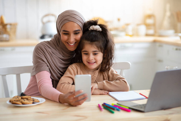 Selfie Fun. Šťastná muslimská žena fotografování s malou dcerou na Smartphone - Fotografie, Obrázek