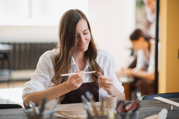 Mujeres jóvenes aprendiendo a esculpir con arcilla durante una lección en un taller en un estudio de arte. - Foto, Imagen