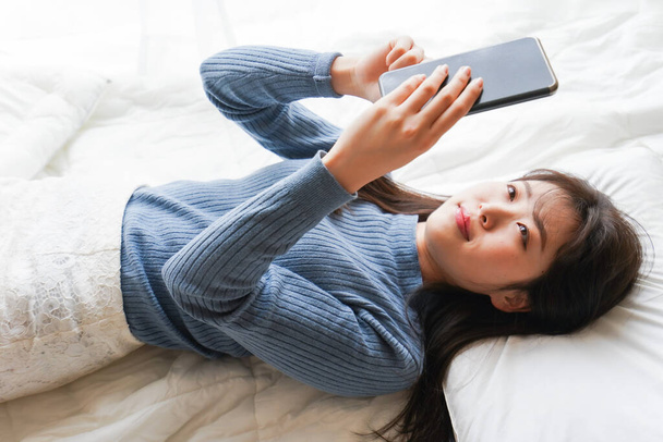 Jovem mulher usando smartphone na cama antes de ir dormir  - Foto, Imagem