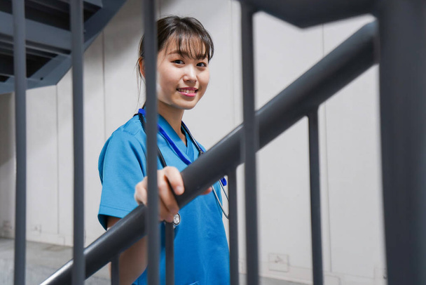 Joven asiática enfermera en escaleras - Foto, Imagen