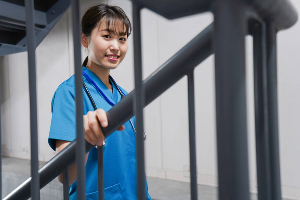 Joven asiática enfermera en escaleras - Foto, Imagen
