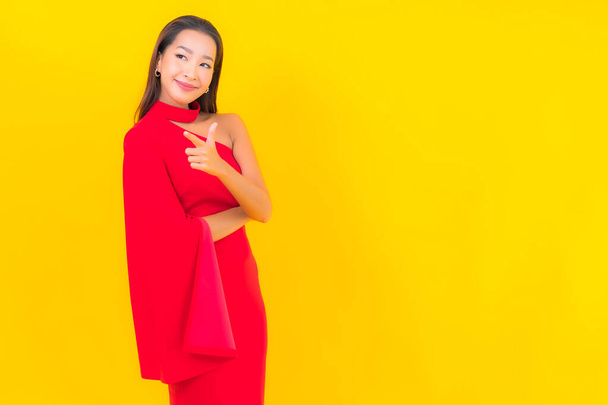 Portret mooie jonge aziatische vrouw glimlach met actie op geel geïsoleerde achtergrond - Foto, afbeelding