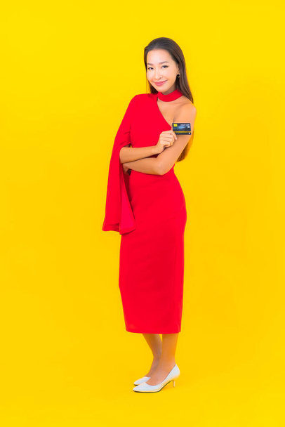 Portret pięknej młodej azjatyckiej kobiety z kartą kredytową na żółtym tle - Zdjęcie, obraz
