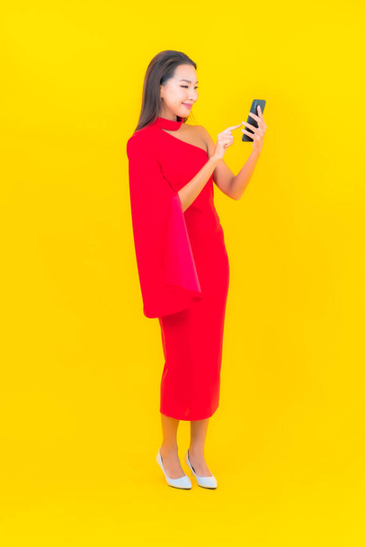 Portrait beautiful young asian woman with smart mobile phone with credit card on yellow background - Fotoğraf, Görsel
