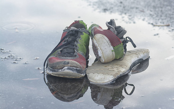 worn out sneaker and stocking on the roadside's puddle. - Foto, Bild