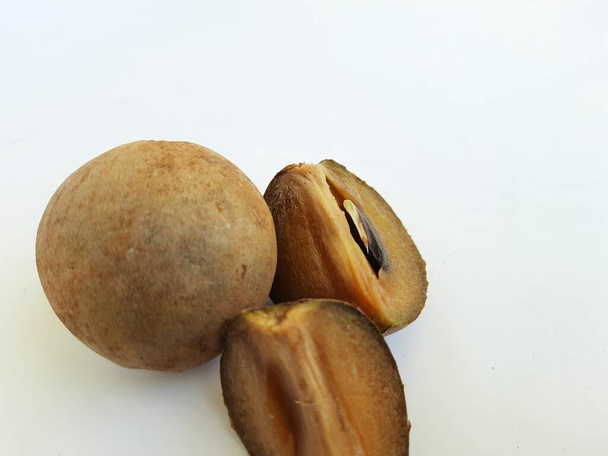 Primer plano de hermoso color marrón completo y medio en rodajas Chickoo o Sapota Fruit aislado sobre fondo blanco - Foto, Imagen