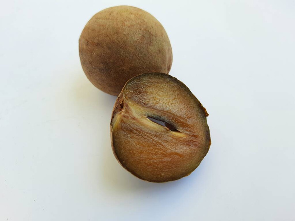 Primer plano de hermoso color marrón completo y medio en rodajas Chickoo o Sapota Fruit aislado sobre fondo blanco - Foto, Imagen