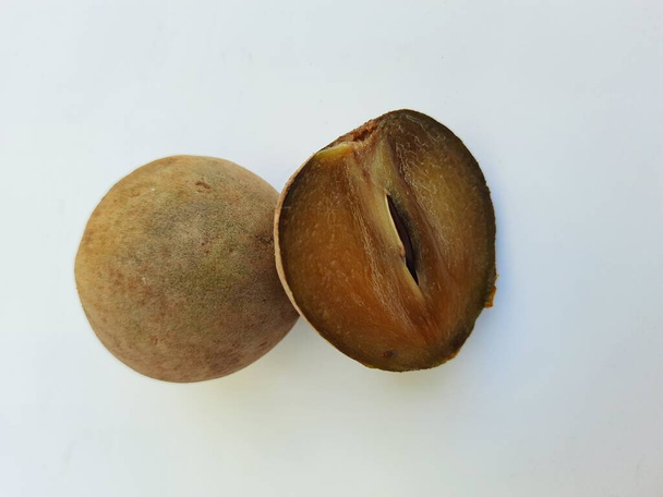 Primer plano de hermoso color marrón completo y medio en rodajas Chickoo o Sapota Fruit aislado sobre fondo blanco - Foto, imagen