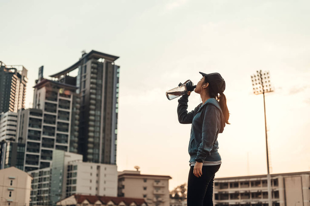 woman athlete thirsty takes a break. she drinking water after running. - Φωτογραφία, εικόνα