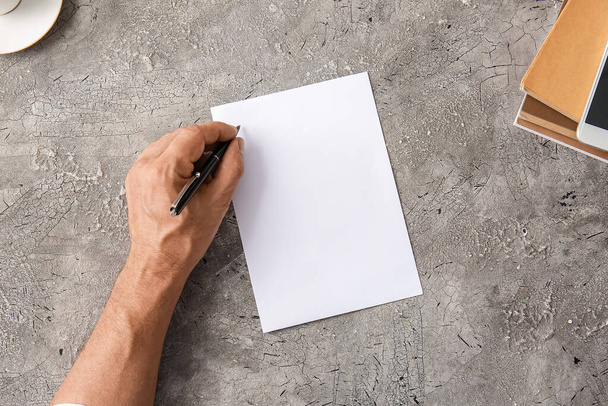 Hoja de papel en blanco y mano masculina sobre fondo gris - Foto, Imagen
