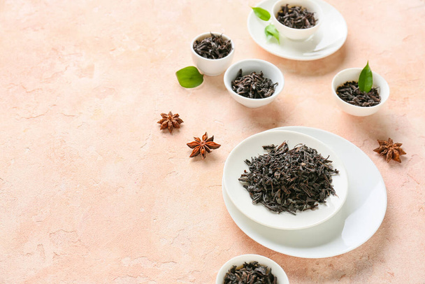 Miski z suchych czarnych liści herbaty na tle koloru - Zdjęcie, obraz