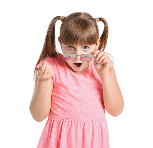 Petite fille surprise portant des lunettes de soleil élégantes sur fond blanc - Photo, image