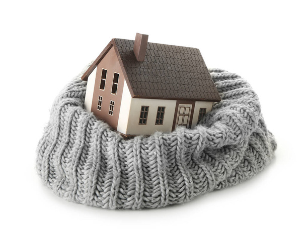 Фигура дома и теплый шарф на белом фоне. Концепция отопительного сезона - Фото, изображение