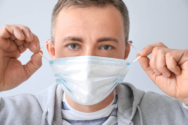 Зрілий чоловік в медичній масці на сірому фоні
 - Фото, зображення
