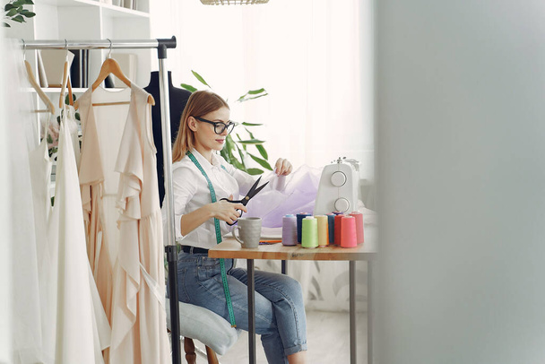 Woman sitting in studio and sew cloth - Foto, Imagem