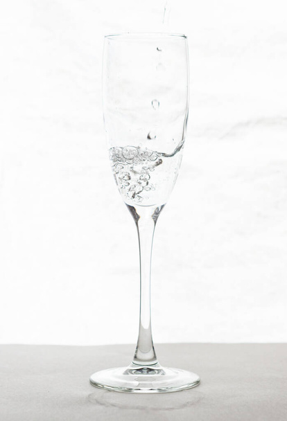 Llenar el agua de la copa de champán aislada sobre un fondo blanco - Foto, Imagen