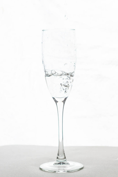 Llenar el agua de la copa de champán aislada sobre un fondo blanco - Foto, imagen