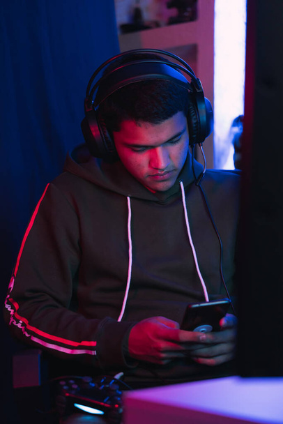 A shallow focus of a Hispanic male gamer texting on a phone while streaming a video game online - Φωτογραφία, εικόνα