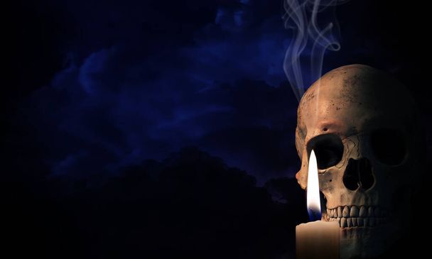 Szkieletowa głowa z zapaloną świecą w ciemnym ciemnym tle. Koncepcja Halloween. - Zdjęcie, obraz