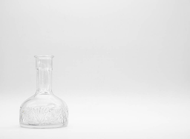 Single empty glass carafe on a white background. Transparent bottle. Front view of the vertical staying colorless jar. - Foto, imagen