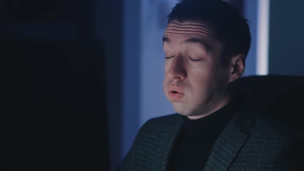 Masentunut mies liikemies työskentelee kannettavassa tietokoneessa myöhään yöllä, kärsii väsymyksestä ja emotionaalisesta uupumuksesta. seurata valo heijastus hänen kasvonsa - Materiaali, video