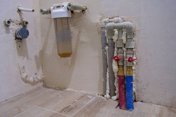 tuyaux métal-plastique pour eau froide et chaude avec robinets. filtre à eau grossière. tuyaux sortant du mur - Photo, image