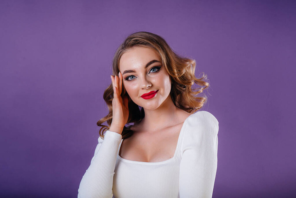 A young beautiful girl shows emotions and smiles in the Studio on a purple background. Girls for advertising - Foto, afbeelding