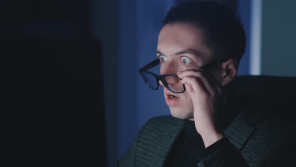 Korkan ve şok olmuş bir adam monitör ekranına bakıyor, gece geç saatlerde bilgisayar dizüstü bilgisayarında çalışırken gözlüğünü çıkarıyor ve ağzını eliyle kapatıyor. Erkek kötü haberden korkar, korkunç mesajı okur.. - Video, Çekim