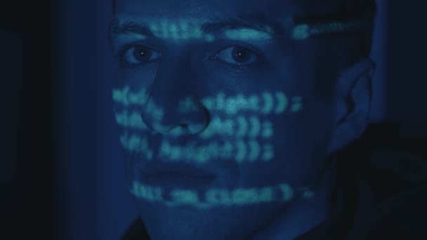 Крупный план портрета ИТ-хакера программиста в очках работающего компьютера, кибератаки на сервер ночью. Программный код отражается на лице. Мужчина виртуальный шпион взлома программного обеспечения в темной комнате - Кадры, видео