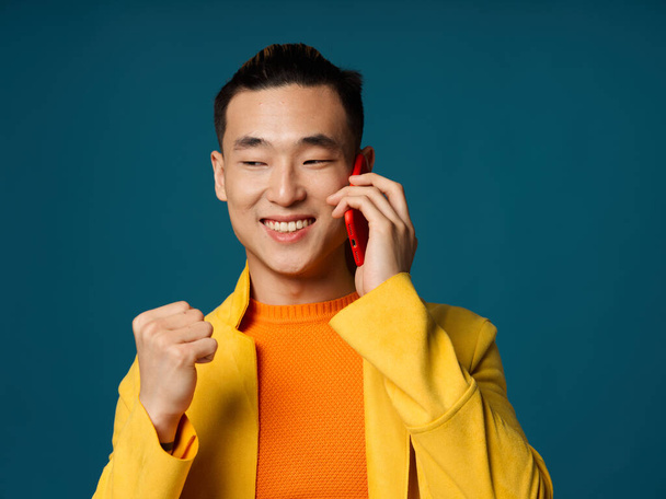 Šťastný asijský muž sevřel ruku v pěst a mluvil do telefonu - Fotografie, Obrázek