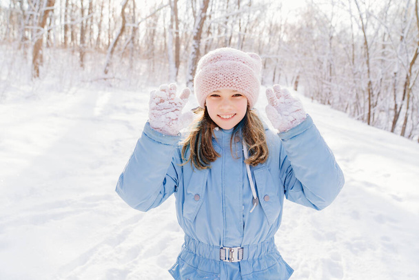 A girl shows snow sticking to pink gloves after playing in snowballs. - 写真・画像