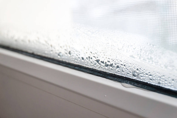 Condensation on PVC window in winter, white plastic window with mosquito net - Fotó, kép