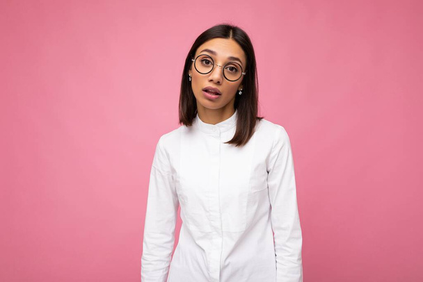Photo shot of beautiful sad upset young brunette woman wearing casual clothes and stylish optical glasses isolated over colorful background looking at camera - Photo, Image