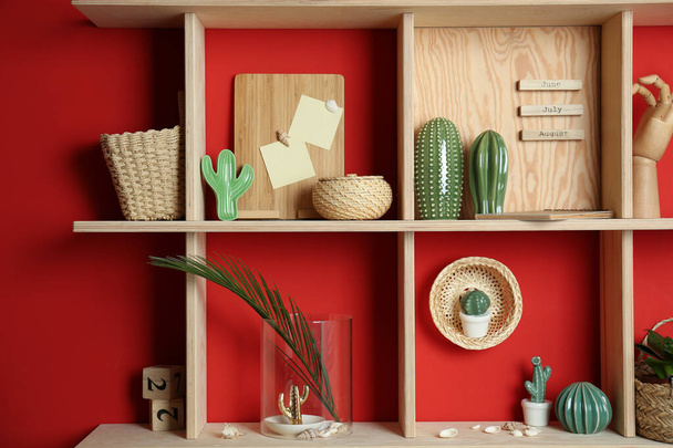 Stylish wooden shelves with decorative elements on red wall - Foto, immagini