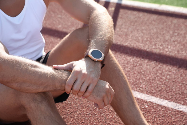 Man with fitness tracker after training at stadium, closeup - Foto, imagen
