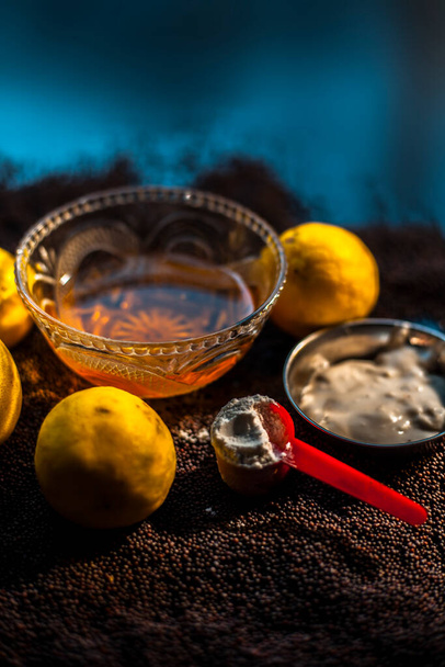 Mustard seed face mask for glowing skin on black surface with raw fresh lemons, mustard seeds, yogurt, honey, and cornflour. - Fotografie, Obrázek