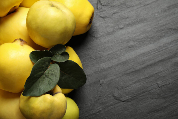 Fresh ripe organic quinces with leaves on black table, closeup. Space for text - Foto, imagen