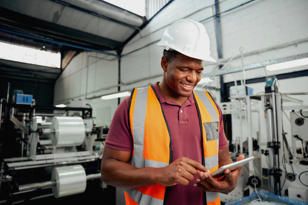 Happy male technician engineer checking process on digital tablet in large factory - Φωτογραφία, εικόνα