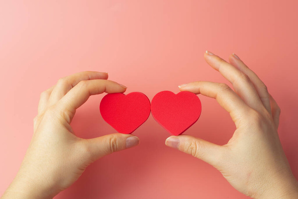 Coeur dans les mains d'une femelle sur un fond coloré. Don, charité, traitement de santé, concept d'aide. Contexte de la Saint-Valentin (14 février) et de l'amour. - Photo, image