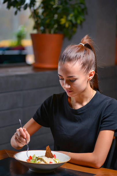 Woman eating salad. Portrait of beautiful smiling woman enjoying a healthy salad in restaurant. Young caucasian female eats healthy food. - Foto, Imagen
