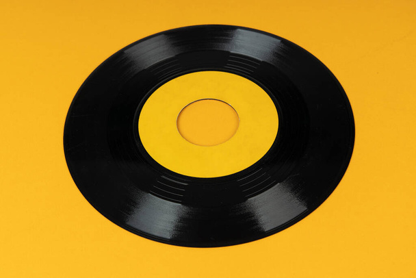 黄色の背景に古いビニールディスク。古いヴィンテージビニールレコード.  - 写真・画像