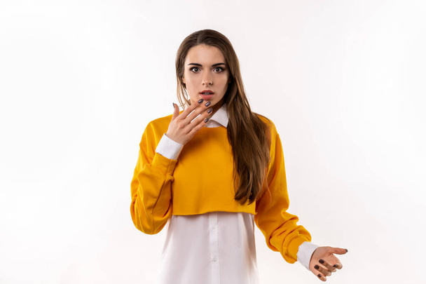Worried and concerned brunette girl in casual clothes cover opened mouth palm and looking with frightened expression, clueless how act, feel embarrassed and worried. Studio shot, white background - Photo, Image