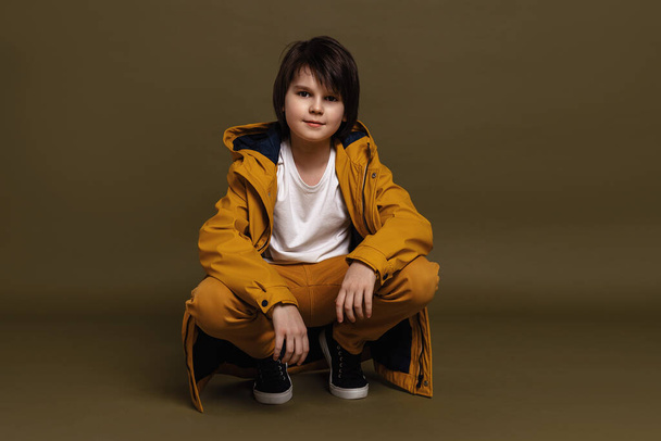 Προσωπογραφία νεαρού αγοριού 11-13 ετών που ποζάρει στο στούντιο πάνω σε πράσινο φόντο. Απλό στυλ. Κομψή γυρίσματα στο στούντιο - Φωτογραφία, εικόνα