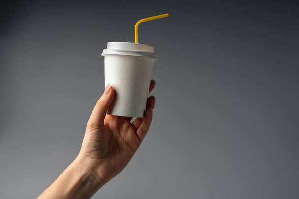 Цвет 2021 года - ярко-желтый. Молодая женщина держит бумажный стаканчик с кофе. Coffee to go life - Фото, изображение