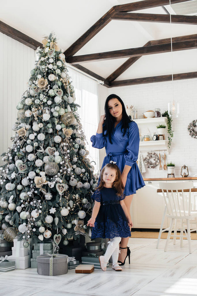 Mom and daughter celebrate and play near the Christmas tree at Christmas. Holiday. - Foto, afbeelding